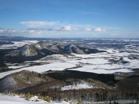 雪で白くなっている晴れの日の山頂からの景色