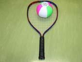 ミニテニスのラケット1本とピンク・白・黄緑の色をしたボールが床に置かれている写真