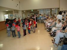福祉施設に子供たちが訪問し踊っている写真